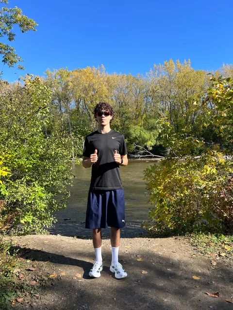 Samy au bord d’une rivière, en tenue de course et avec des lunettes de soleil.